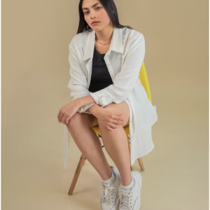 Cette chemise blanche longue est confectionnée dans un tissu fluide et léger, parfait pour un look à la fois structuré et décontracté.