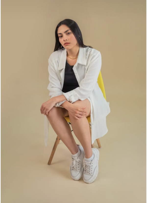 Cette chemise blanche longue est confectionnée dans un tissu fluide et léger, parfait pour un look à la fois structuré et décontracté.